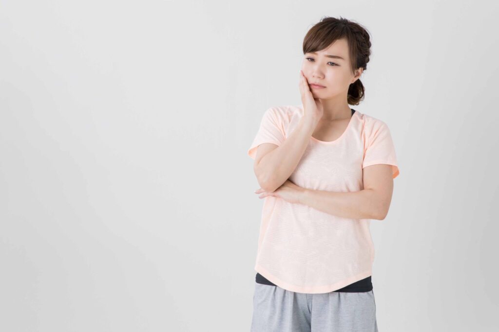 口元を押さえて悩んでいる女性