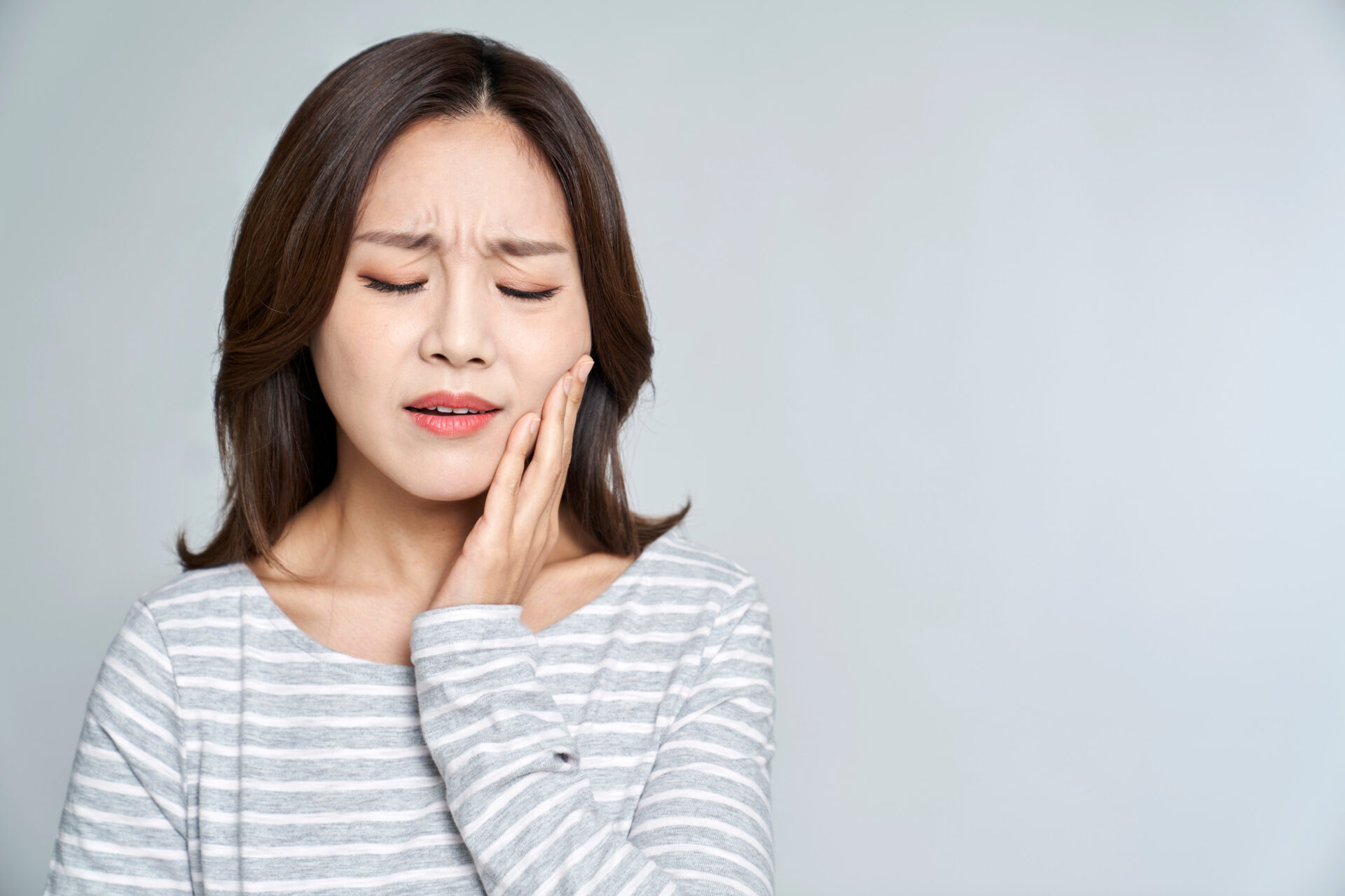 顎を抑えて歯の痛みに耐える女性