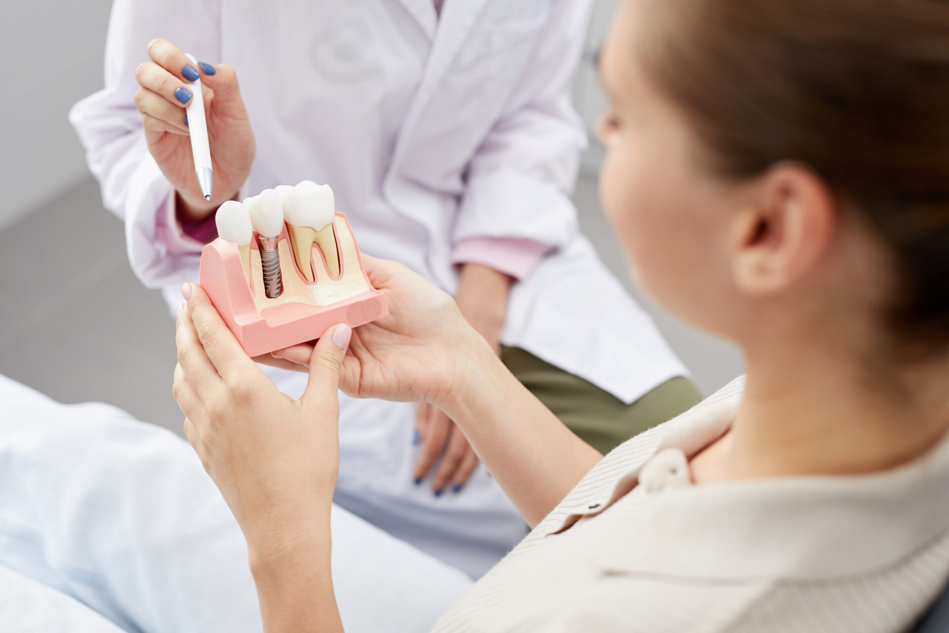 医師から説明を受ける歯の模型をもつ女性患者