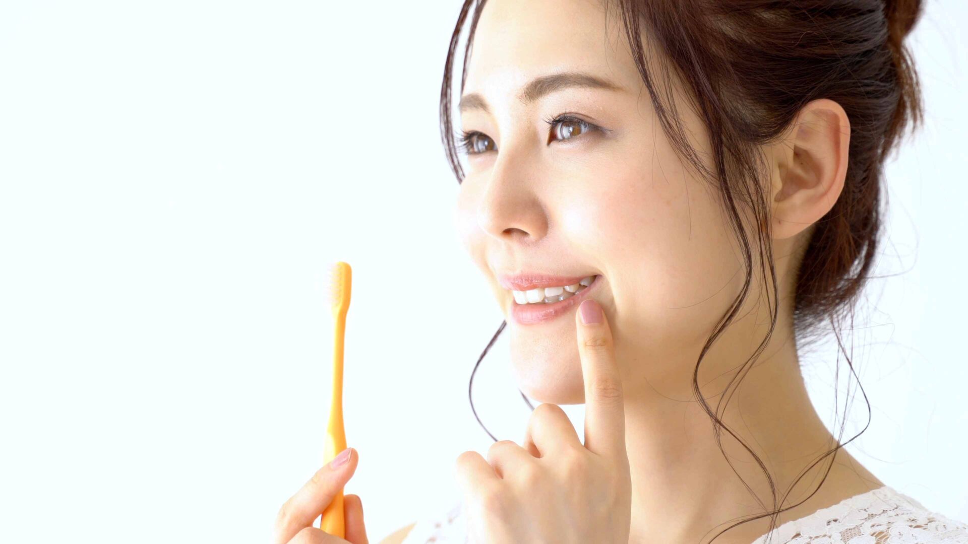 歯ブラシを持ち口元に手を当てている女性